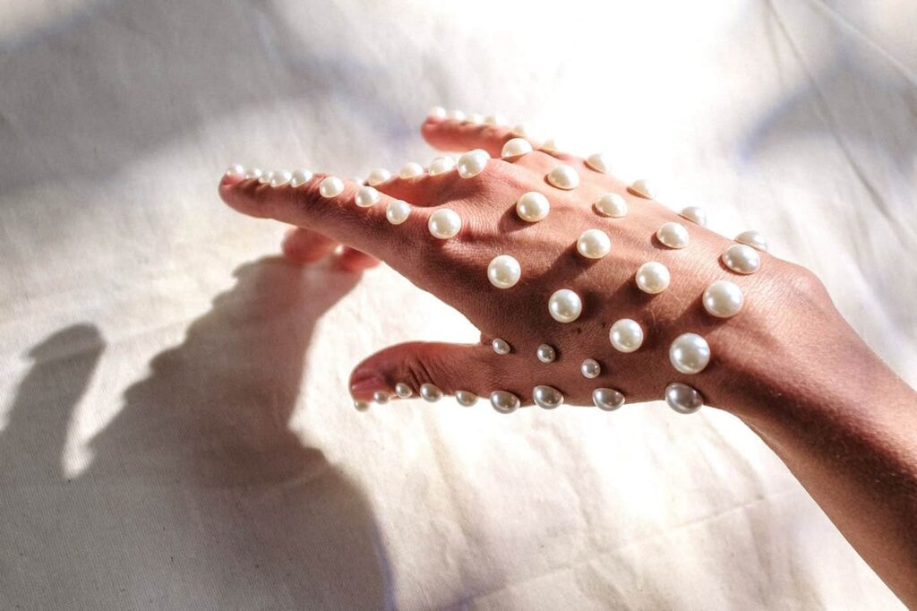 Hand wearing pearl jewelry in soft light