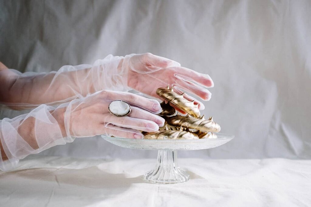 Gloved hands handling gold jewelry on a glass stand